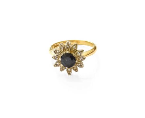 An 18 Carat Gold Sapphire and Diamond Cluster Ring, the round cut sapphire in a white claw setting, within a petal motif bord