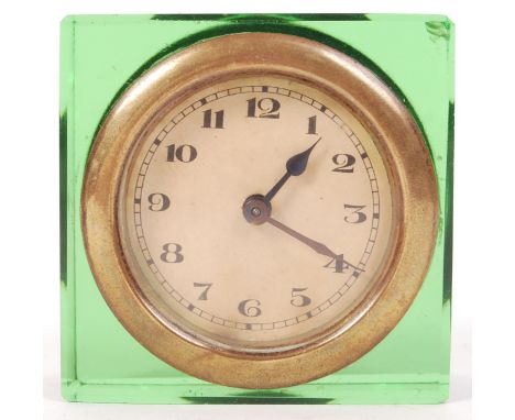 An antique 1920's early car dashboard brass clock. Later set within a green cut glass mount, converting it to a mantel clock.
