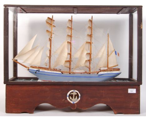 A museum quality hand made antique style wooden scratch built model of a sailing ship raised on a naturalistic sea base. The 