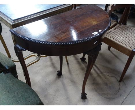 A mahogany demilune foldover card table, raised on cabriole legs with claw and ball feet.