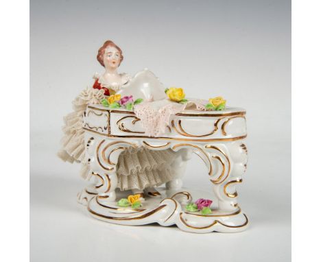 Beautiful hand-painted figurine depicting an elegant lady playing the piano, wearing a dress adorned with many layers of lace