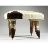 A SMALL HIDE STOOL on four horn legs, 1 ft. 2 in. high.