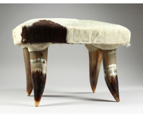 A SMALL HIDE STOOL on four horn legs, 1 ft. 2 in. high.
