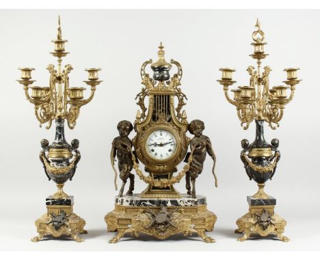 A LARGE FRENCH GILT METAL AND MARBLE THREE PIECE CLOCK GARNITURE, the clock of lyre shape wth two cupids holding a garland co