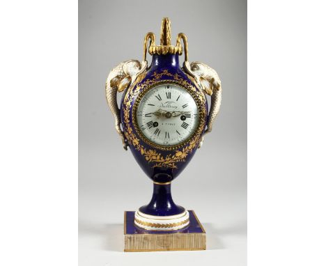 A GOOD LOUIS XVITH STYLE URN SHAPED PORCELAIN CLOCK, blue and gilt decoration.  Dolphin handles and square base, by Noel Lero