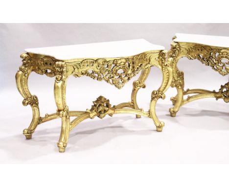 A PAIR OF GILDED AND MARBLE TOP CONSOLE TABLES with white speckled marble tops, gilt bases with curving legs, pierced frieze 