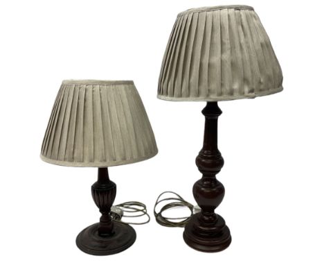 Turned wooden table lamp with a circular plinth base together with a similar example, both with pleated lampshades, tallest e