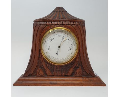 An early 20th century barometer and thermometer, in an oak case carved two guns and two pickelhaubes, 26 cm high, and two bar