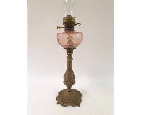 An oil lamp, with a pink glass well, on a brass base decorated flowers, 82 cm highNo shade, surface wear to well with no visi