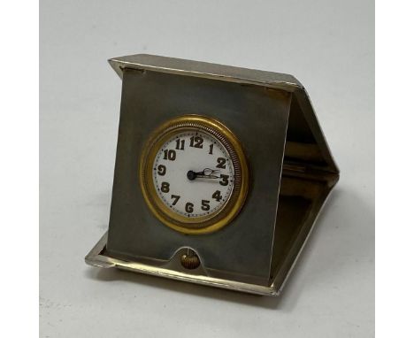A travelling timepiece, the 2.5 cm diameter enamel dial with Arabic numerals in a silver case, with engine turned decoration,