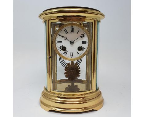 A mantel clock, the 7.5 cm diameter enamel dial with Roman numerals, fitted an eight day movement, in an oval brass four pill