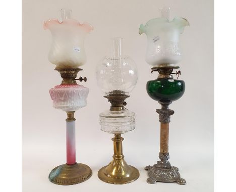 An oil lamp, with a pink glass well, 70 cm, another with a green glass well, 71 cm, and another with a clear glass well, 61 c