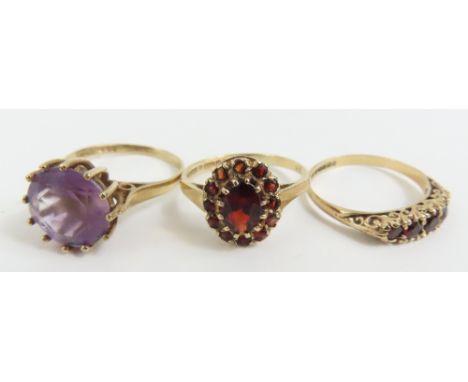 A 9ct gold garnet cluster ring, finger size M 1/2; a 9ct gold amethyst single stone ring, finger size K 1/2; and a 9ct gold g