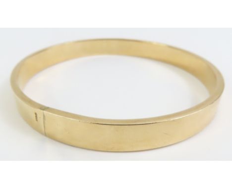 A plain gold solid bangle, 8.5mm wide, 7.2cm internal diameter, tests as 9ct gold, 17.1g gross