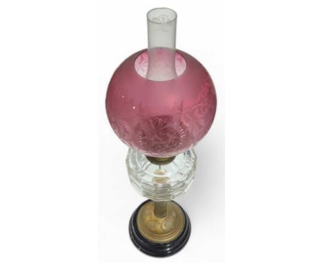 A Victorian oil lamp with etched cranberry glass shade clear glass reservoir, brass pillar and black glass base, 69cms high i