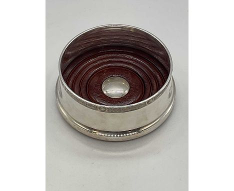 An Elizabeth II hallmarked silver and wooden based Irish bottle coaster with Celtic inspired band to the rim, Dublin 1975, di