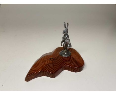 A vintage hare car mascot from an Alvis 12/50 mounted on a polished pitch pine shaped base, length 23.5cm.