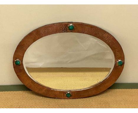 An Arts and Crafts copper oval wall mirror with bevelled plate, decorated frame set with four Ruskin type roundels, 69 x 51cm