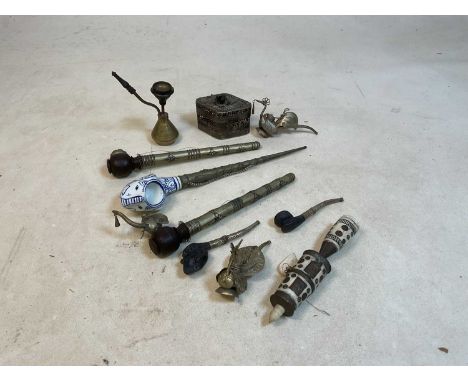 A group of metal stemmed pipes, one with ceramic bowl, one with bone detail, also a white metal cricket cage of lozenge form.