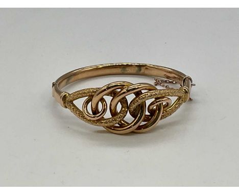 An Edwardian 9ct yellow gold hinged bangle with pierced knot upper platform with textured detail, hallmarked for Chester 1907