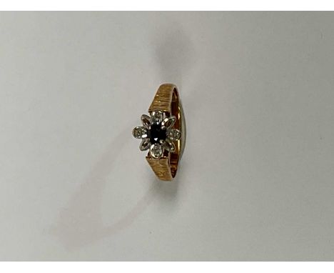 An 18ct yellow gold sapphire and diamond chip floral ring with textured detail to the shoulders, size M, approx. 2.9g.