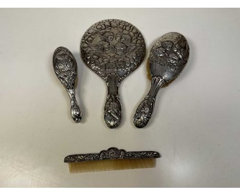 A George V hallmarked silver three piece dressing table set decorated with embossed Reynold's angels, comprising brush, comb 