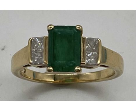 An 18ct yellow gold emerald and diamond ring, the emerald cut emerald set with four princess cut diamonds to the shoulders, s