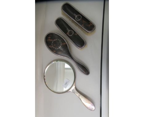 A four items silver backed and tortoiseshell dressing table set&nbsp; comprising a hand mirror and three beakers&nbsp; London
