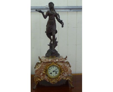 A late 19thC French marble cased mantel clock, surmounted by a Spelter figure of a girl; the 8 day movement faced by an ename