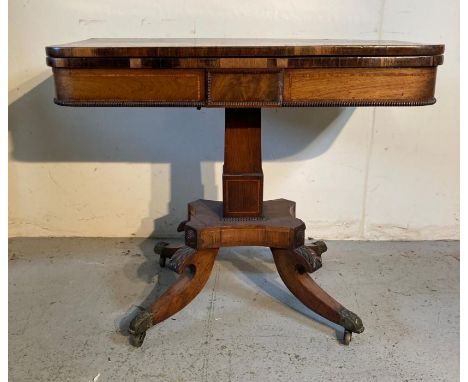 A mahogany fold over card table on out swept legs with brass paw feet and castors (H74cm W92cm D45cm)