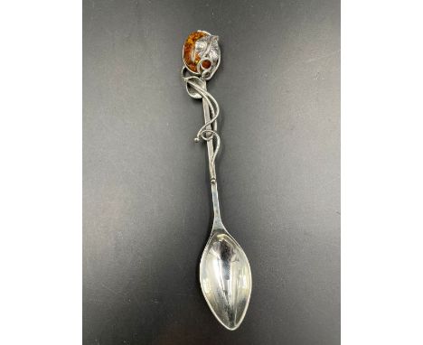 A silver caddy spoon of Art Nouveau form with an amber top.