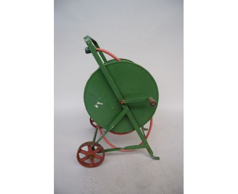 A vintage green painted metal hose winder with cast iron wheels and wooden handle and later garden hose