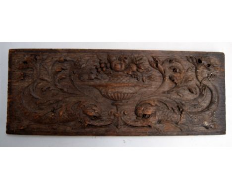 A renaissance style walnut panel in the mannerist taste carved with an urn of fruit and two dolphins 14 x 36cm