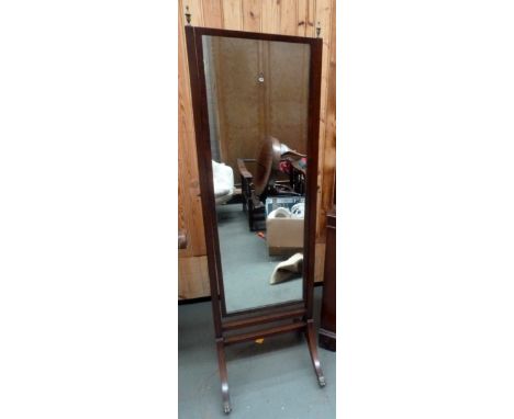 A floor standing dressing mirror on claw and ball feet with brass finials to top