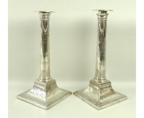 A pair of George III silver candlesticks, in the style of Robert Adam, the composite columns chased with swags, below laurel 