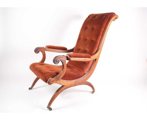A William IV mahogany framed plantation-style open armchair with moulded and carved scroll back and "X" frame with red velvet