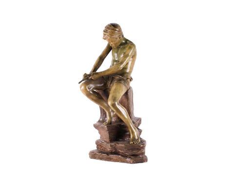 A Goldscheider terracotta figure of a young Arab boy whittling a stick with a knife. Seated on a rocky perch. Bearing impress