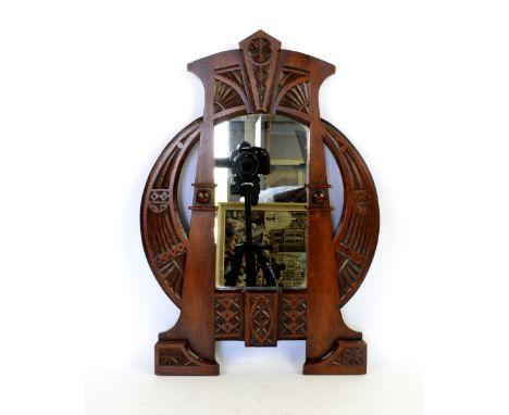 An Art Nouveau mahogany wall mirror in the style of Carlo Bugatti, tapering rectangular form with flanking buttresses carved 