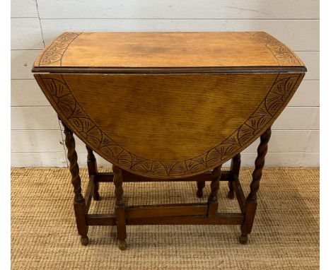 An oak gate leg table with carved top and barley twist legs (H72cm W108cm D74cm extension W37cm down)