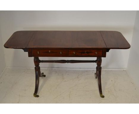 An early 19th Century cross banded mahogany sofa table, drop flaps, two drawers and two dummy drawers, twin supports with bra