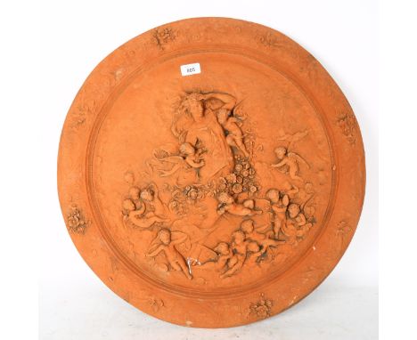 A circular terracotta plaque, with embossed cherub decoration, width 61cm 
