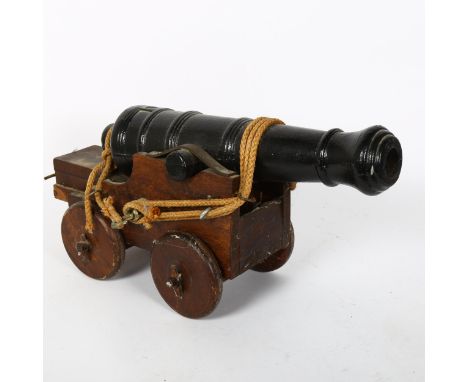 A small scale cast-iron garden cannon, on oak carriage base, barrel length 41cm 