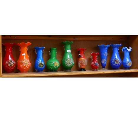 A shelf of colourful 1950s glass vases with applied floral decoration, tallest 25cm 