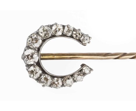 A diamond stick pin, the horseshoe-shaped terminal with graduated old-cut diamonds in claw settings, two colour metal mounted