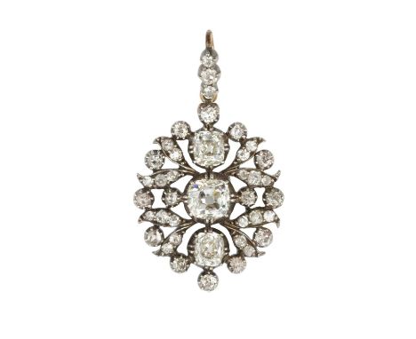 A late Victorian diamond pendant/brooch, the openwork foliate cartouche centred with a trio of cushion-shaped old-cut diamond