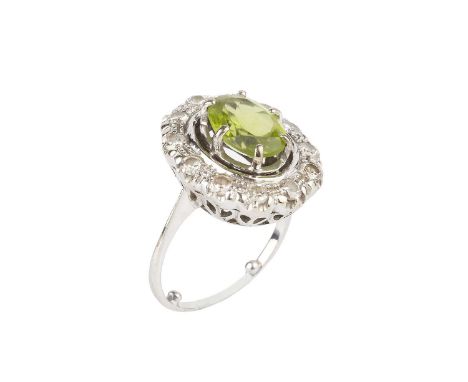 A peridot and diamond cluster ring, the oval mixed-cut peridot claw set within a pierced border of round brilliant-cut diamon