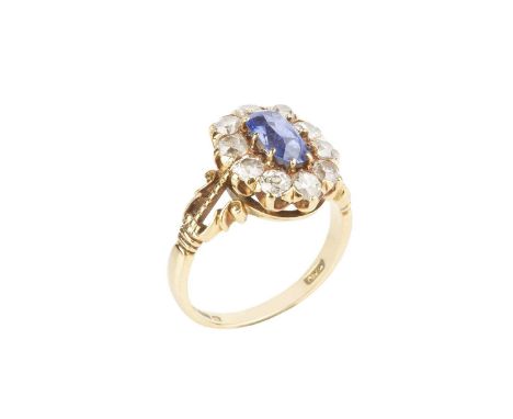 A sapphire and diamond cluster ring, the oval mixed-cut sapphire claw set within an old-cut diamond border, between scrolled 