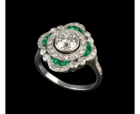 An emerald and diamond panel ring, the principal transitional-cut diamond in millegrain collet setting, within a quatrefoil-s