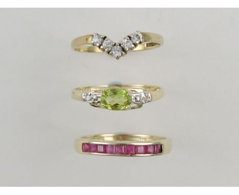 A ruby dress ring, the emerald cut stone channel set on a yellow metal band stamped 375; together with peridot and diamond dr