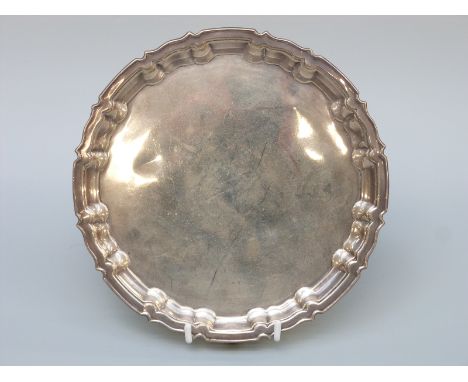 A George V hallmarked silver salver with shaped edge, raised on three feet, Sheffield 1916 maker William Hutton & Sons Ltd., 
